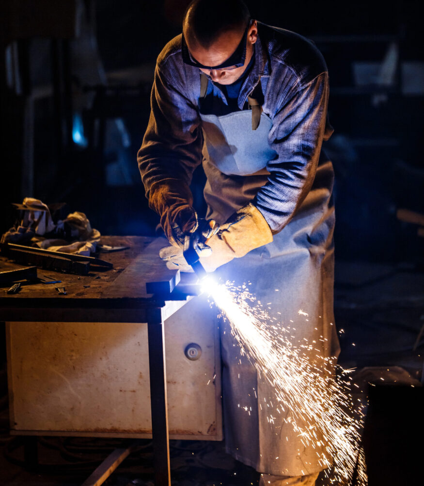 Worker cutting metal with plasma equipment on plant.